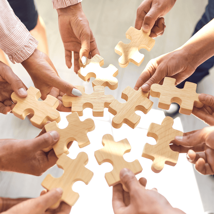 A group of hands holding puzzle pieces- New York Puzzle Company/Janet Hill 1000 pieces jigsaw puzzles - Gizmo Gifts