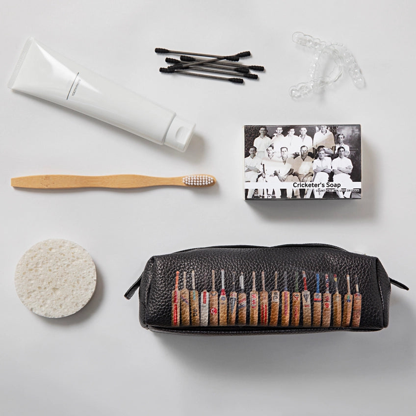 Collection of grooming items including a toothbrush, tube of cream, and black leather case with tools on a light gray background.
