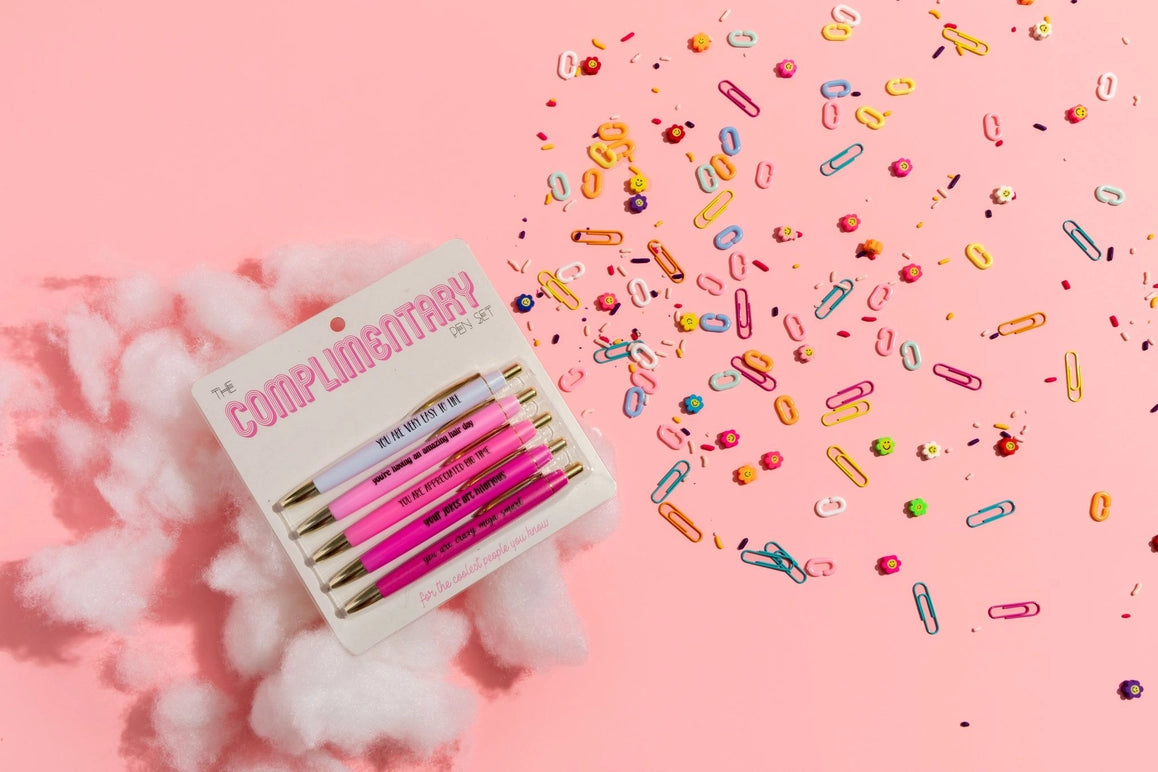 Set of pink pens on a pink background with colorful paper clips.