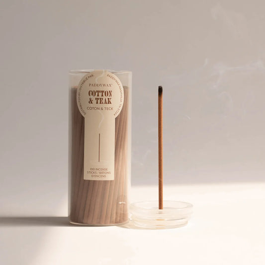 Incense sticks in a cylindrical packaging with an incense stick next to it on a light background