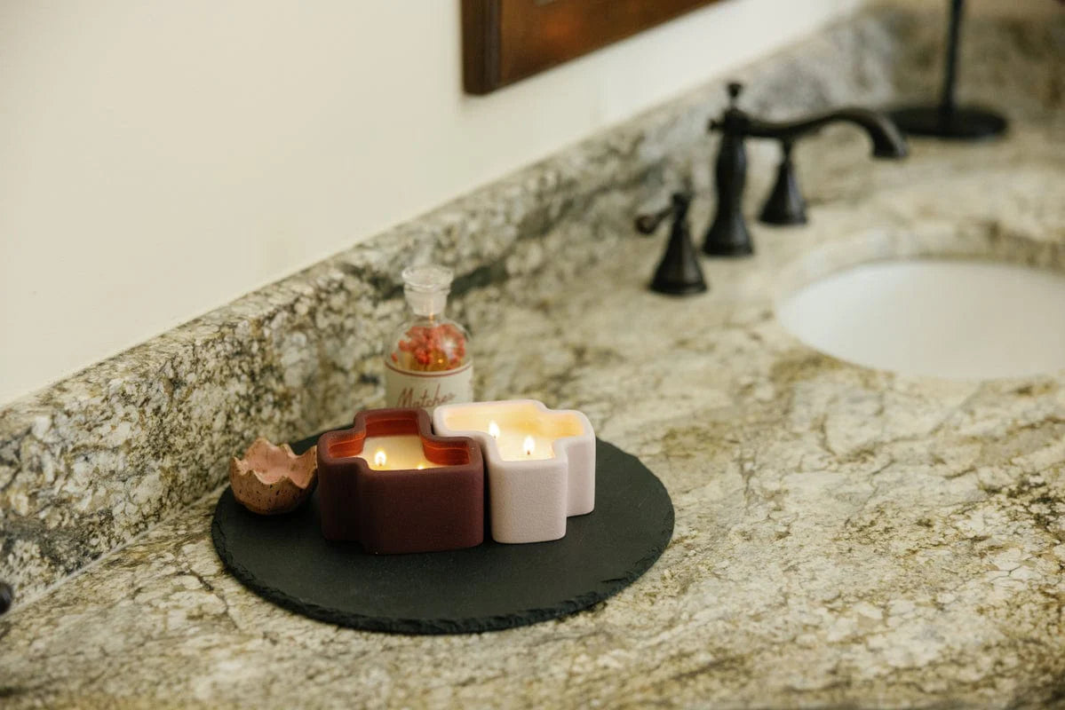 Paddywax jigsaw duo lit candles on a bathroom counter.
