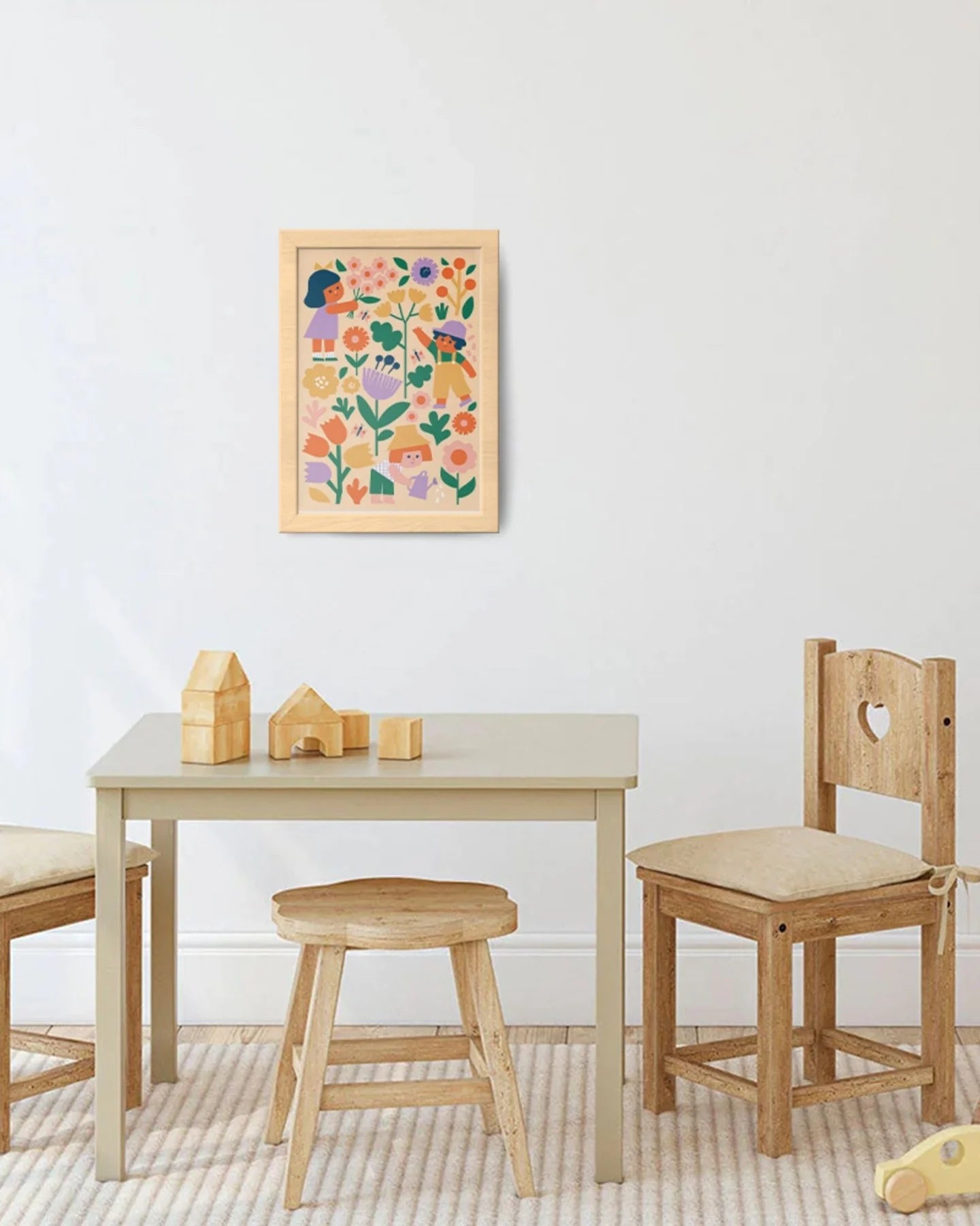 Children's wooden table and chairs with a colorful floral painting on a white wall.