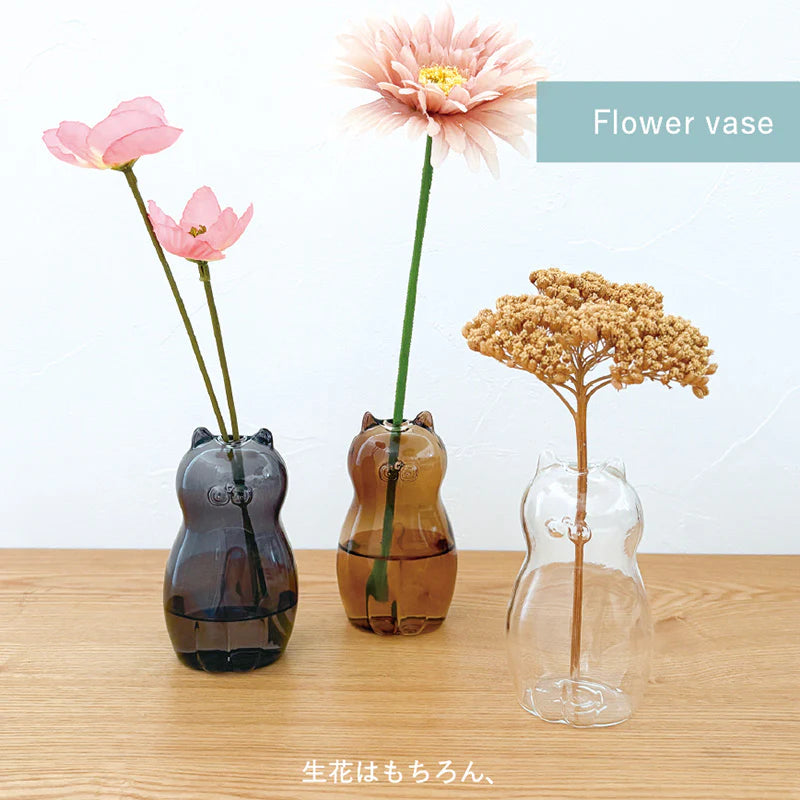 Three cat-shaped vases with flowers on a wooden surface