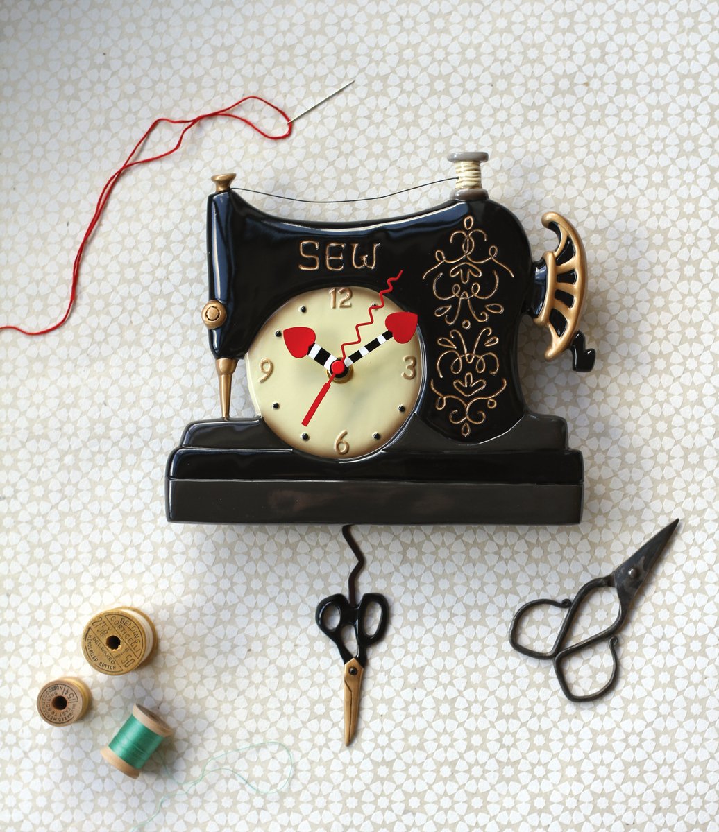 Vintage-style sewing machine clock with scissors and thread on a textured surface