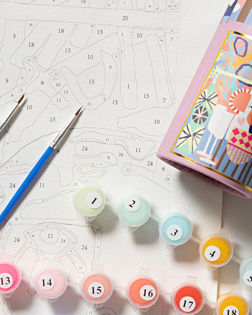 Color swatches with numbers, paintbrushes, and a patterned book on a white surface