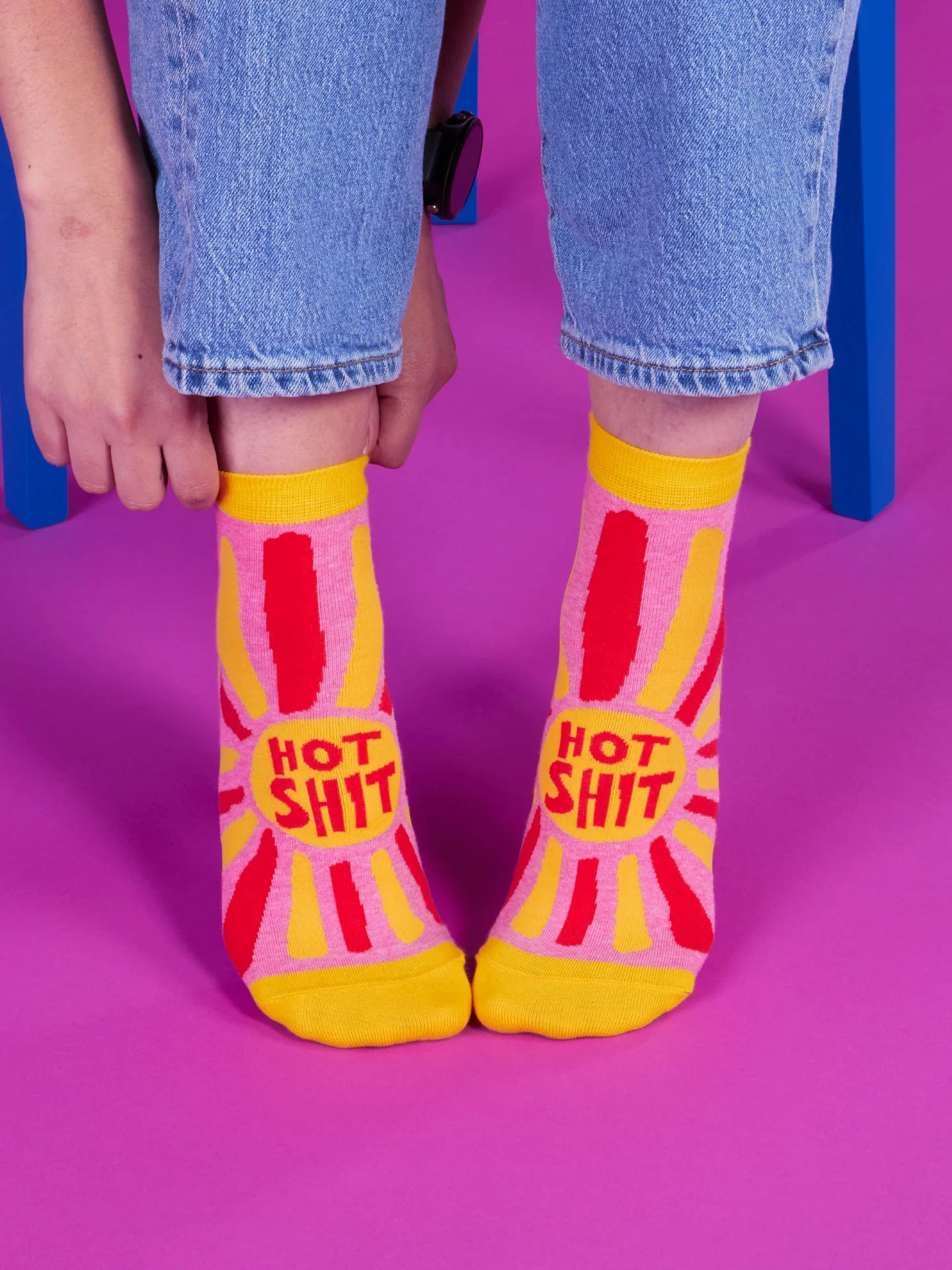 Person wearing colorful socks with text on a pink background