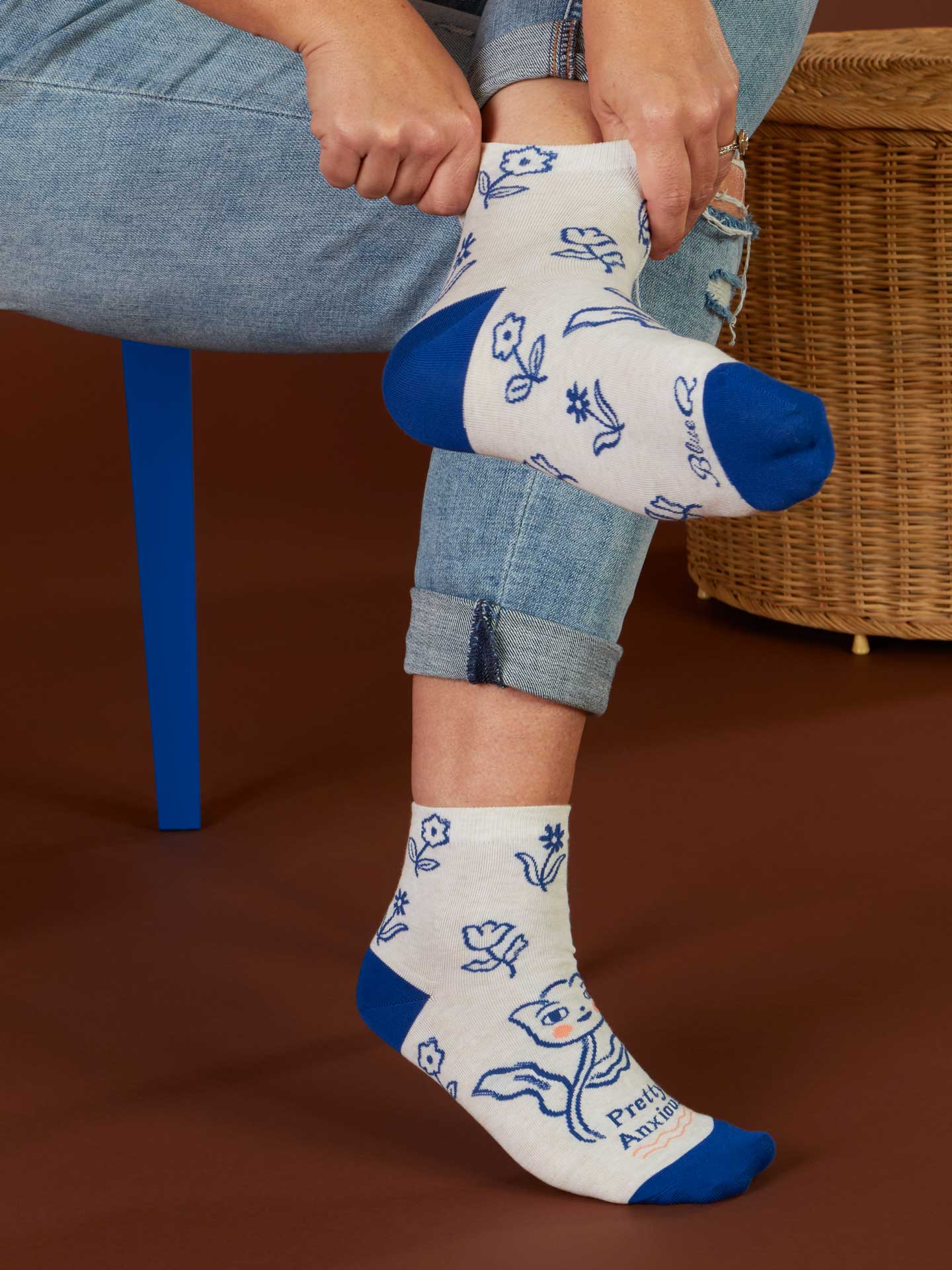Person wearing white socks with blue accents and animal prints, sitting on a brown surface.