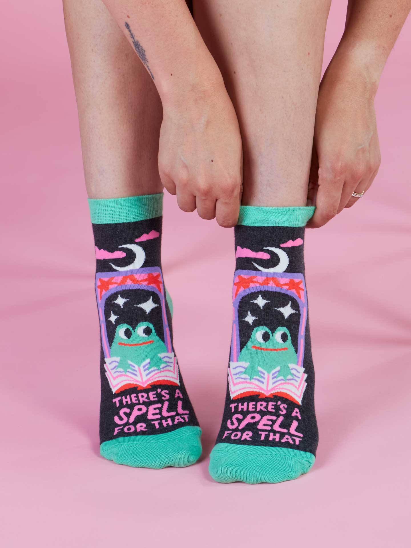 Person wearing socks with a colorful design and text on a pink background