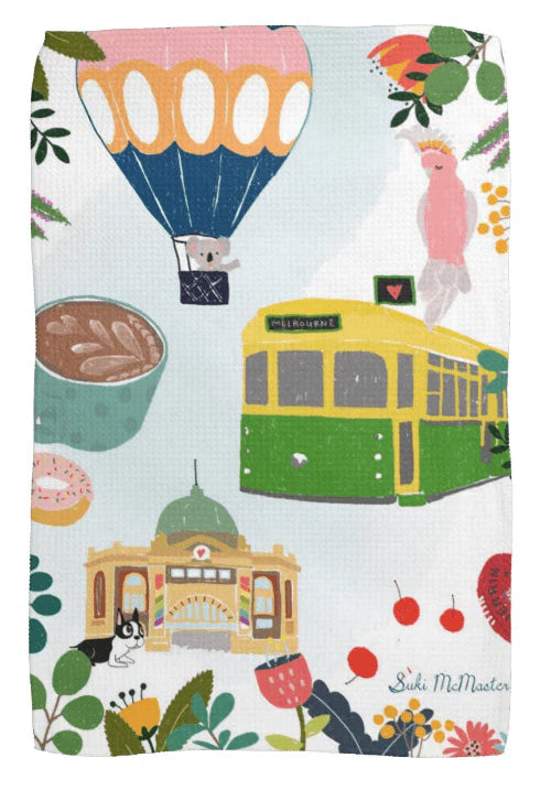 Suki McMaster tea towel with colorful design including a hot air balloon, Melbourne tram, and various elements on a white background.