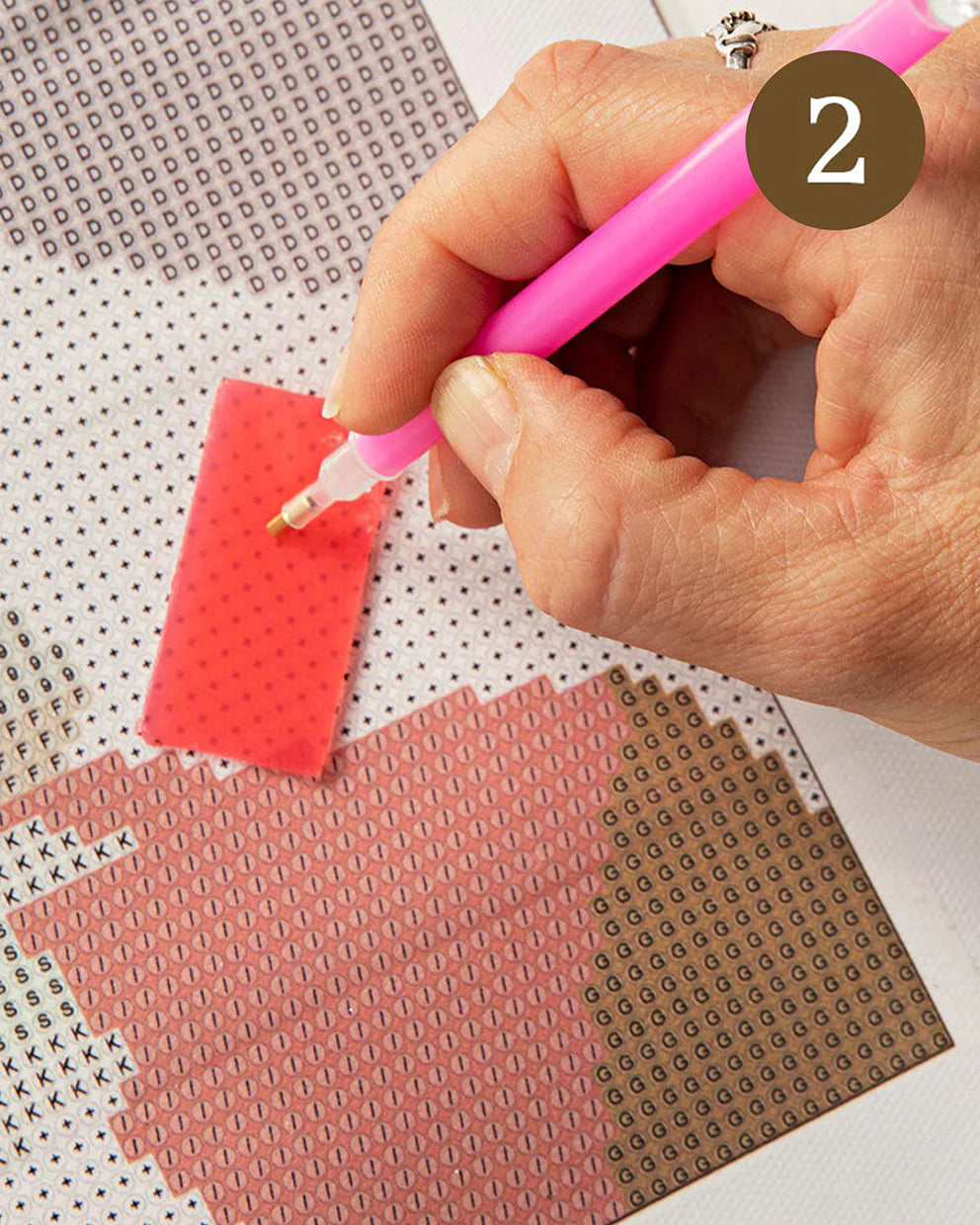 Hand using a pink tool on a grid-patterned surface