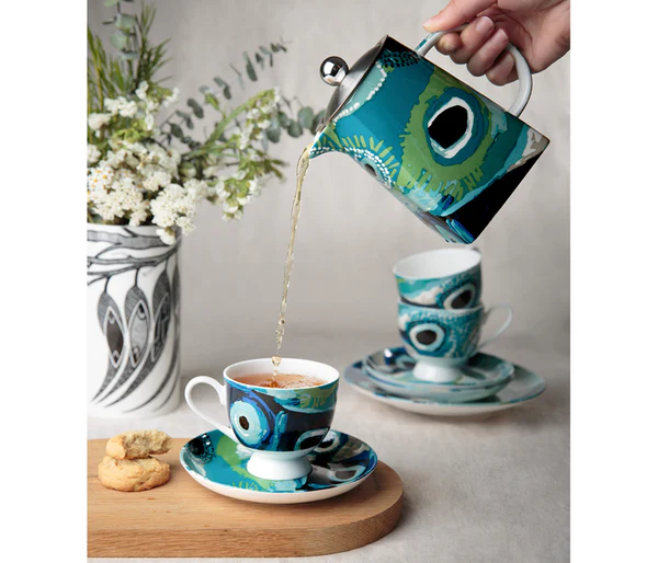 A lifestyle picture of a hand pouring tea into the teacup by Aboriginal artist May Wokka Chapman. The teapot is by the same artist.