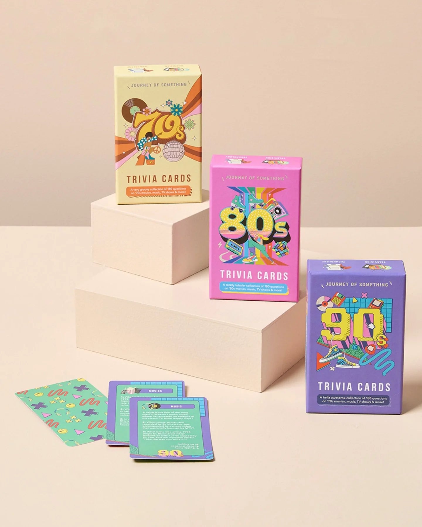Three boxes of trivia cards themed for different decades on a beige background