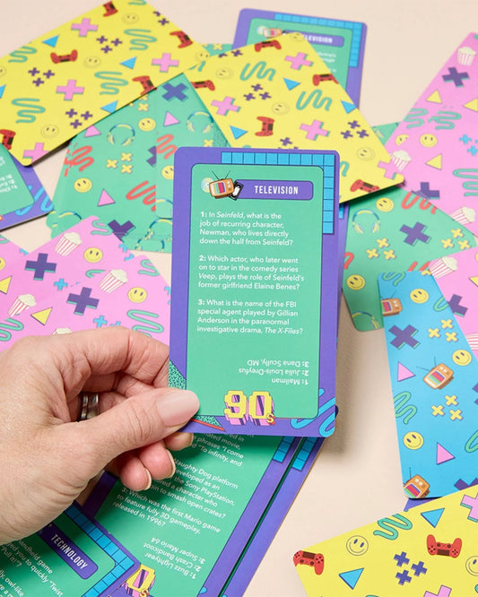Hand holding a colorful card with text and graphics on a table with more cards.