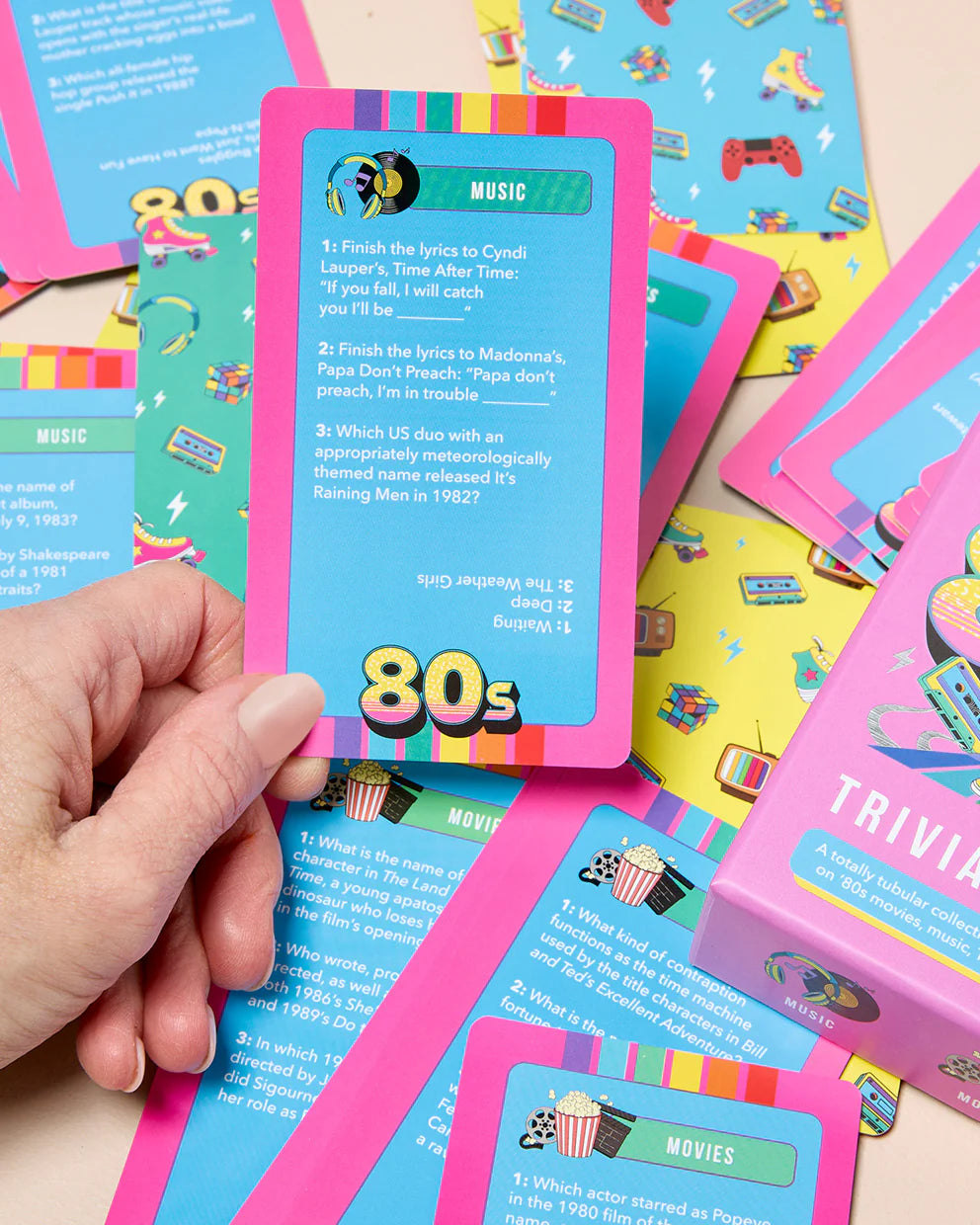 Colorful trivia cards themed around the 80s held by a hand with more cards in the background.