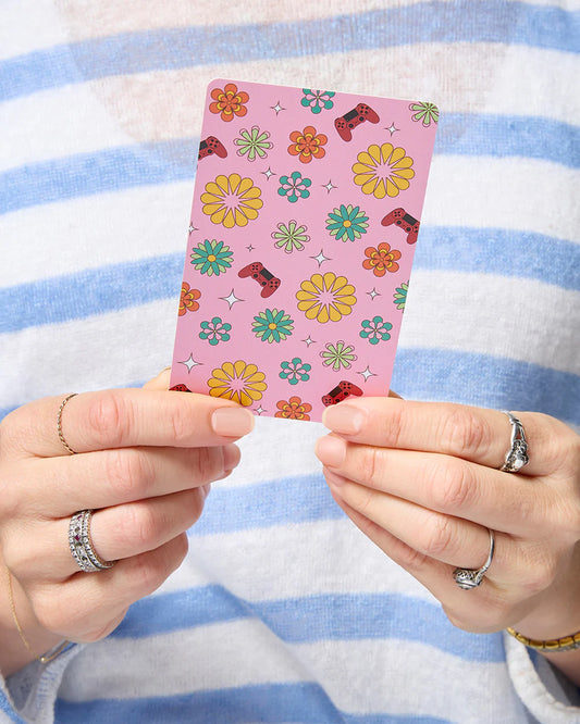 Person holding a pink card with colorful patterns against a striped background