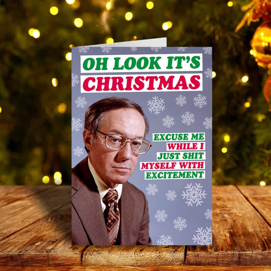 Oh look it's Christmas greeting card on a wooden table setting and festive lights in the background.