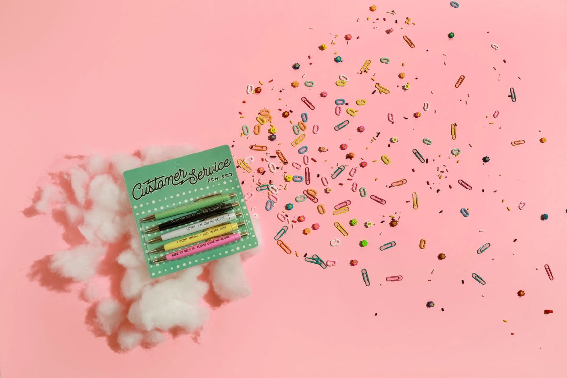 Colorful pen set with 'Customer Service' text on a pink background with cotton and sprinkles.