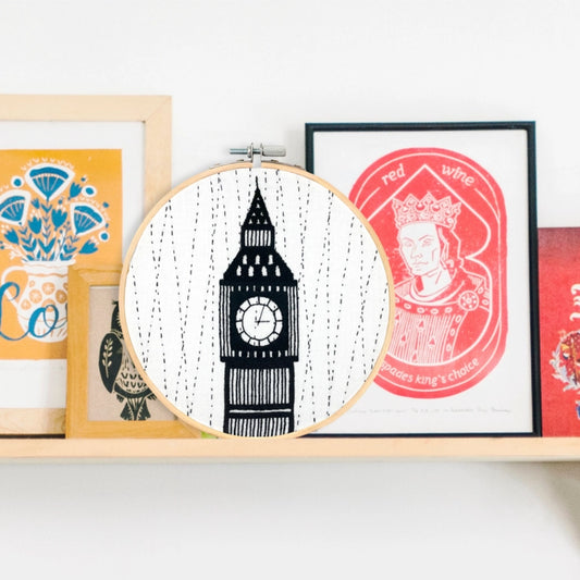 Big Ben clock-tower embroidery design sitting on shelf amongst other graphic artworks.