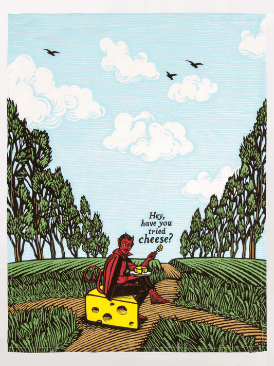 BLUEQ Teatowel - Hey,have you tried cheese? Hey,have you tried cheese? -A picture of a red devil sitting on a block of Swiss cheese and tempting the observer with a cheese board. The background is filled with green fields and rows of trees on either side .A blue sky completes the scene with three birds overhead!