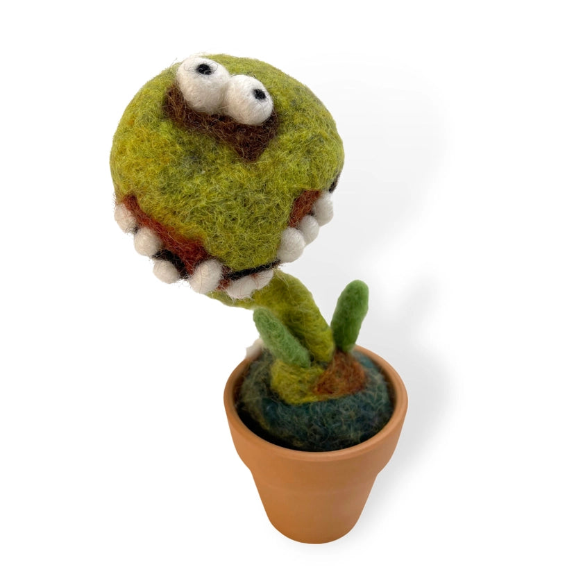 A closeup of the green felt decoration known as "Bob" the potted cactus. It has two felt eyes and a toothy smile , meanwhile it is placed on a white background.