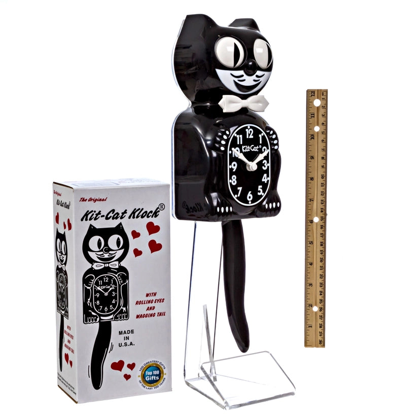 Black cat-shaped clock with packaging and a ruler for scale on a white background