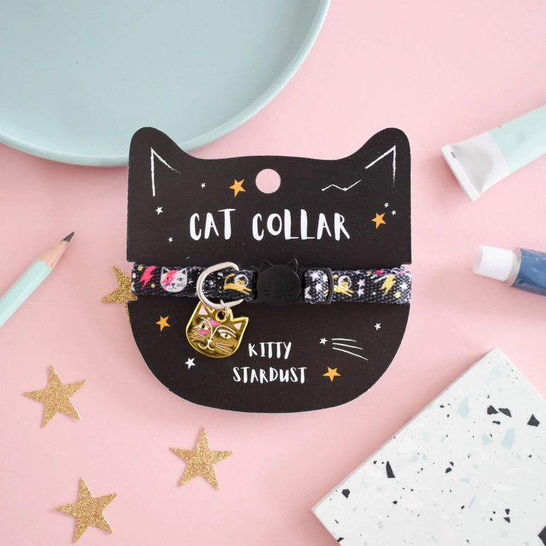 Cat collar with 'Kitty Stardust' design on a black cat-shaped card against a pink background.