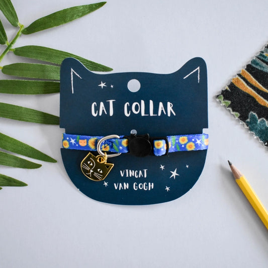 Cat collar with Van Gogh design on a blue card with cat illustration, surrounded by green leaves and a pencil.