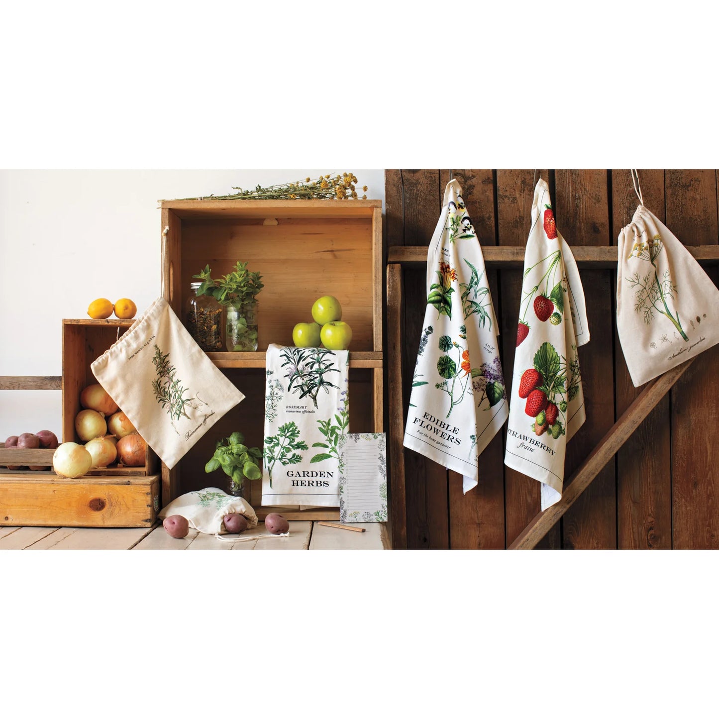 Set of kitchen towels with garden-themed designs on a wooden shelf and wall.