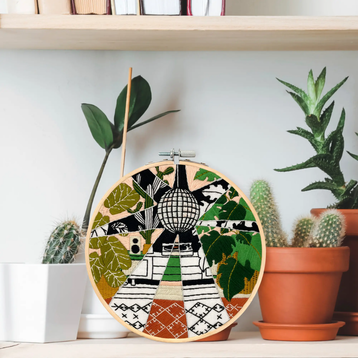 Embroidery&Sage Disco plants design hoop placed n a shel amongst cactus plants
