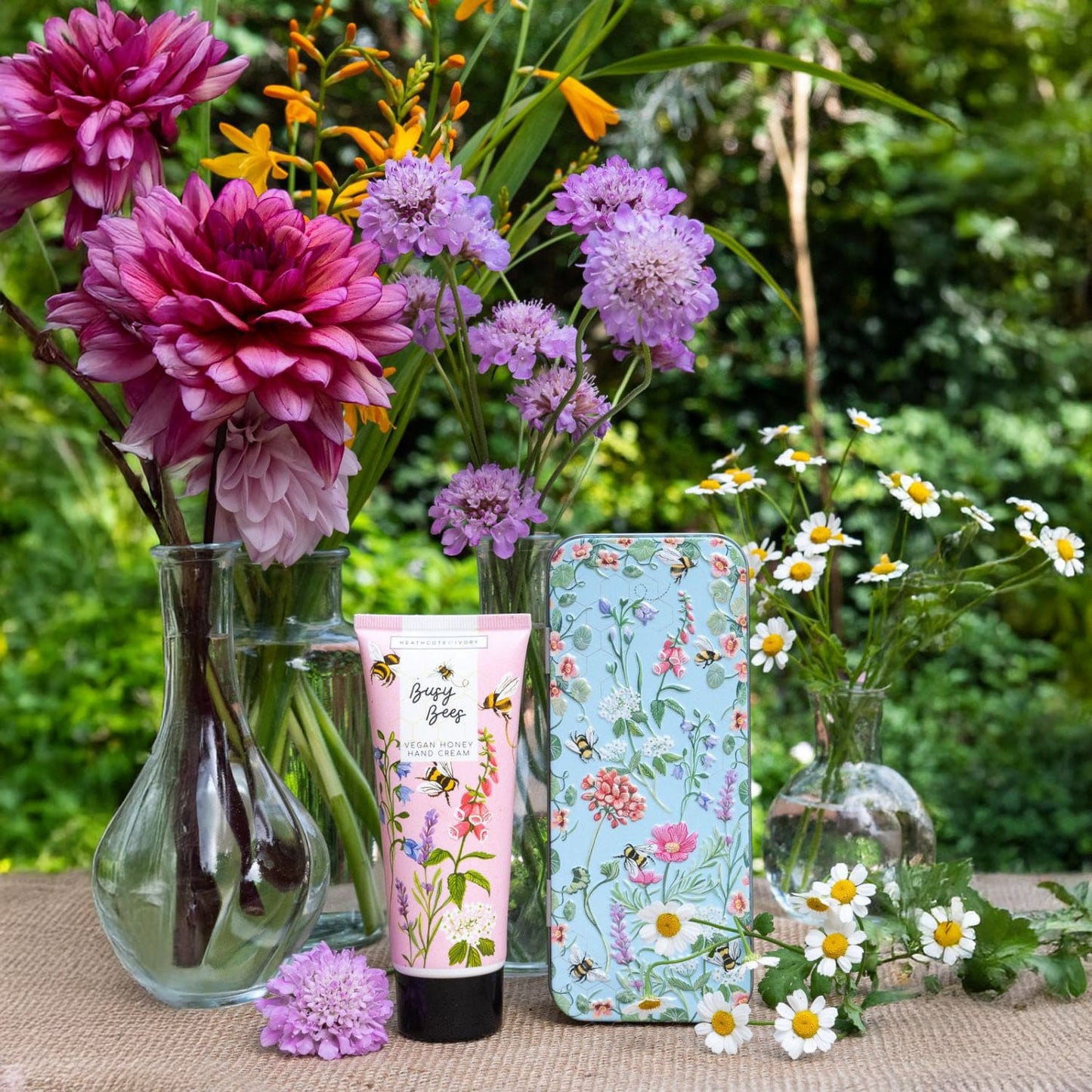 Product with floral design on a table surrounded by flowers outdoors