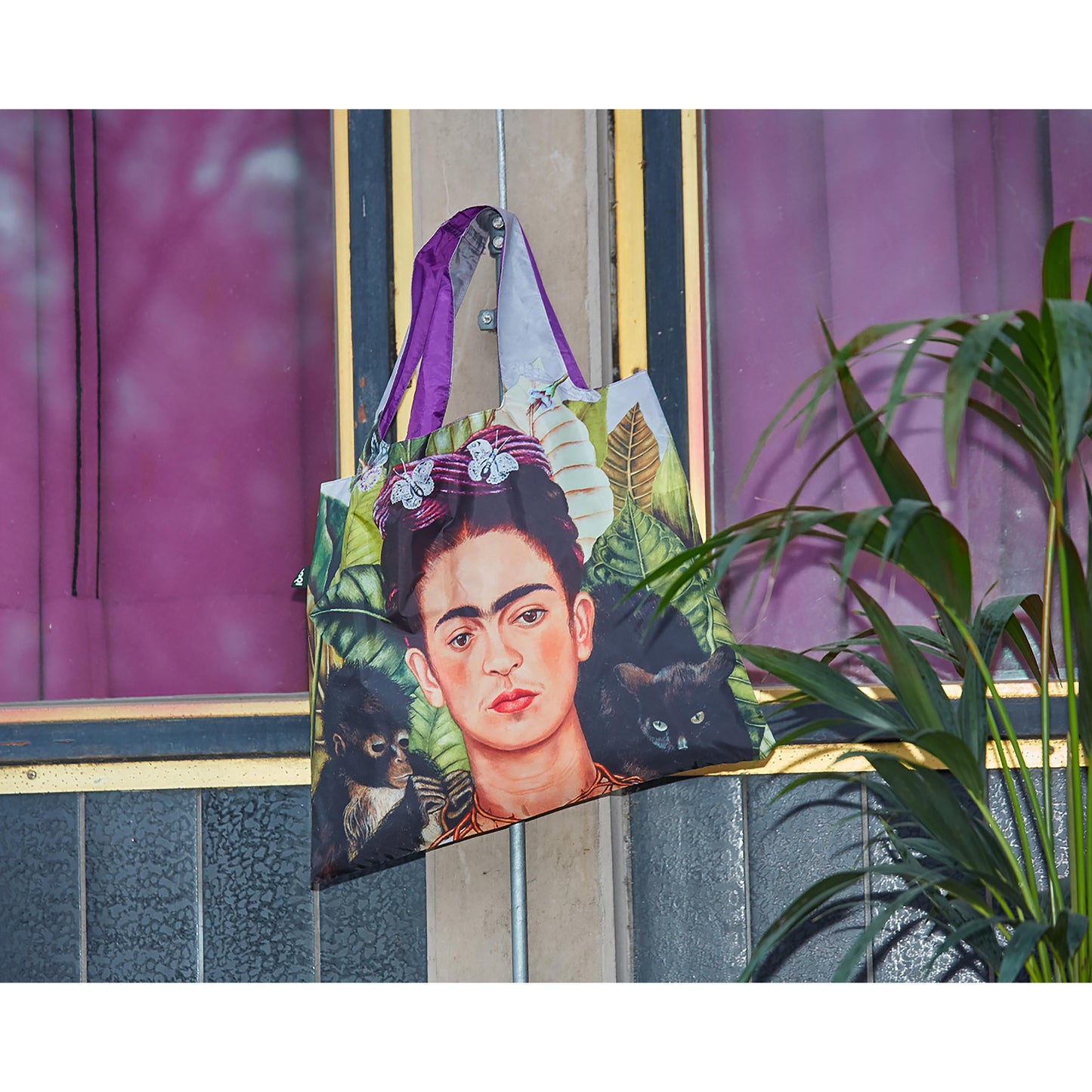 Tote bag with Frida Kahlo design hanging on a door handle.