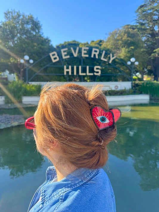 Person with a decorative hair clip in front of the Beverly Hills sign.