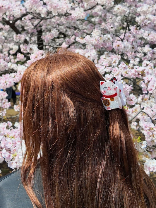 Person with a hair clip shaped like a cat in front of cherry blossom trees