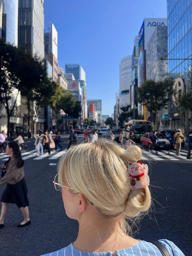 Person with a bun and lucky cat hair clip in an urban setting