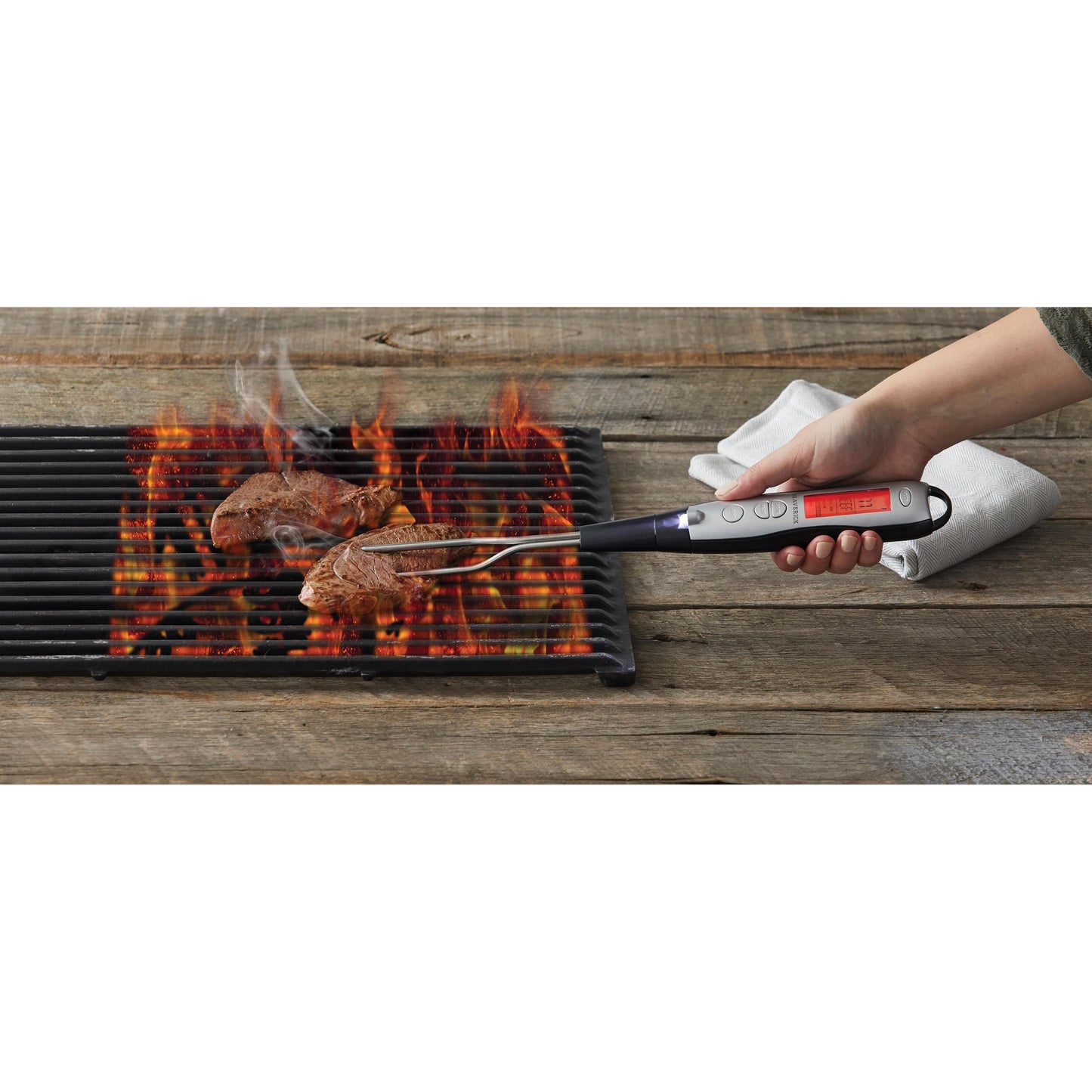 Person using a handheld grill with digital display to cook meat on a wooden surface.