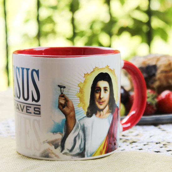 Mug with a religious design featuring a portrait and text, placed outdoors.