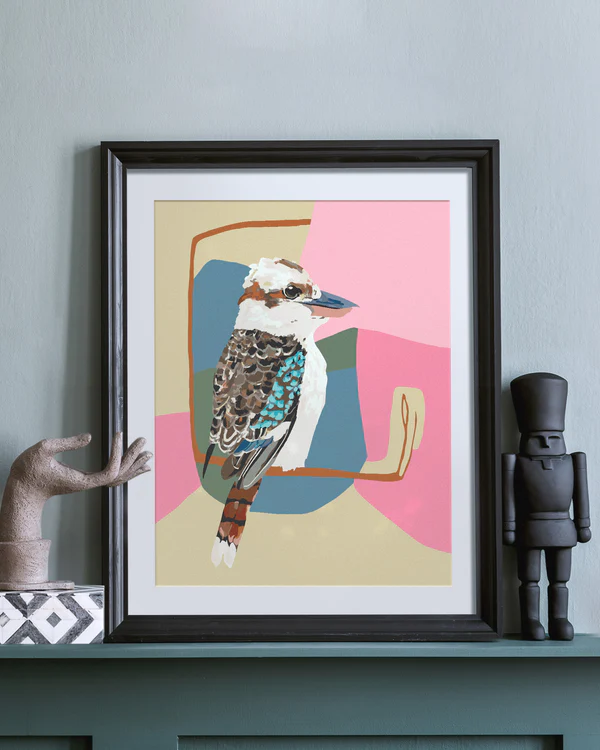 Framed artwork of a colorful Kookaburra bird on a shelf with decorative items.