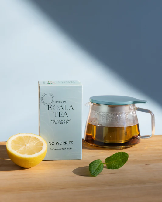 Koala Tea package with a glass teapot and lemon on a wooden surface