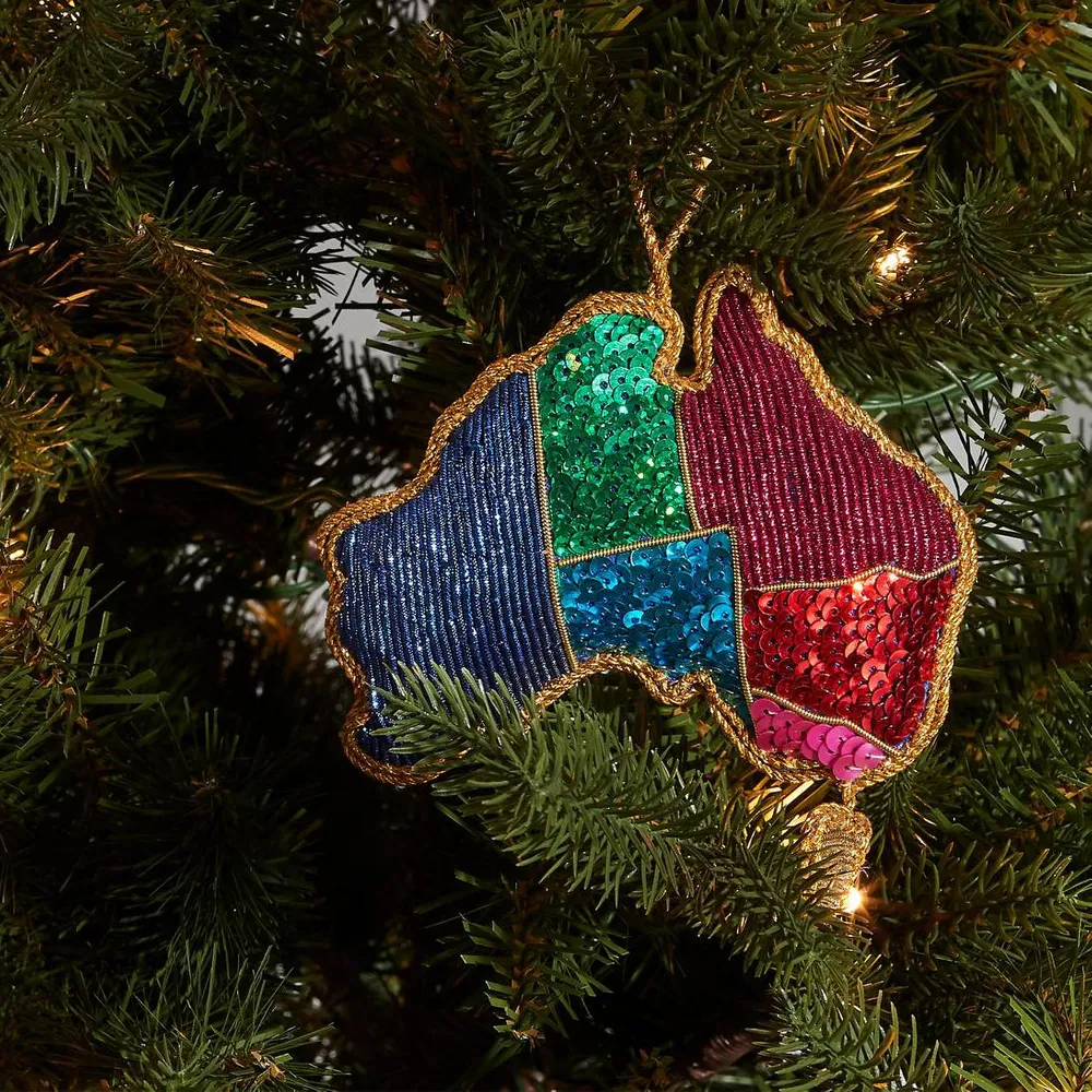 Colorful sequin ornament shaped like a Australia hanging on a Christmas tree.
