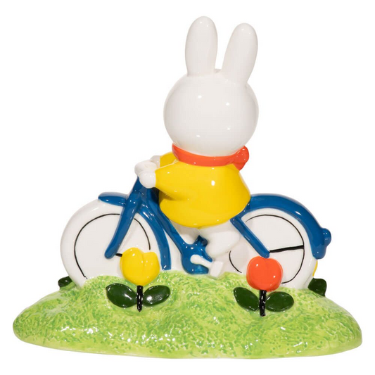 Figurine of a white rabbit on a bicycle with flowers on a green base