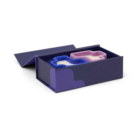 Two jigsaw shaped candles in a purple box on a white background