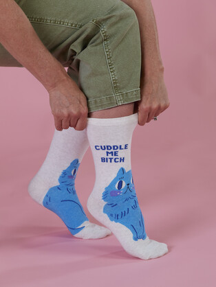 Person wearing socks with cat designs and text on a pink background
