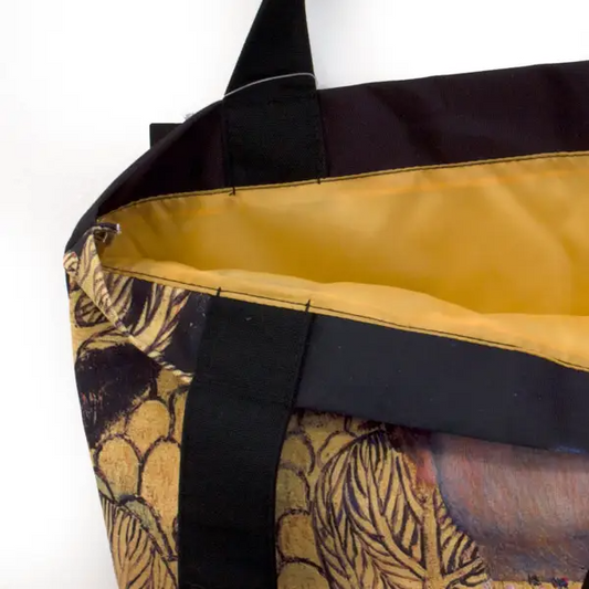 Close-up of a black bag with yellow interior and patterned exterior on a white background