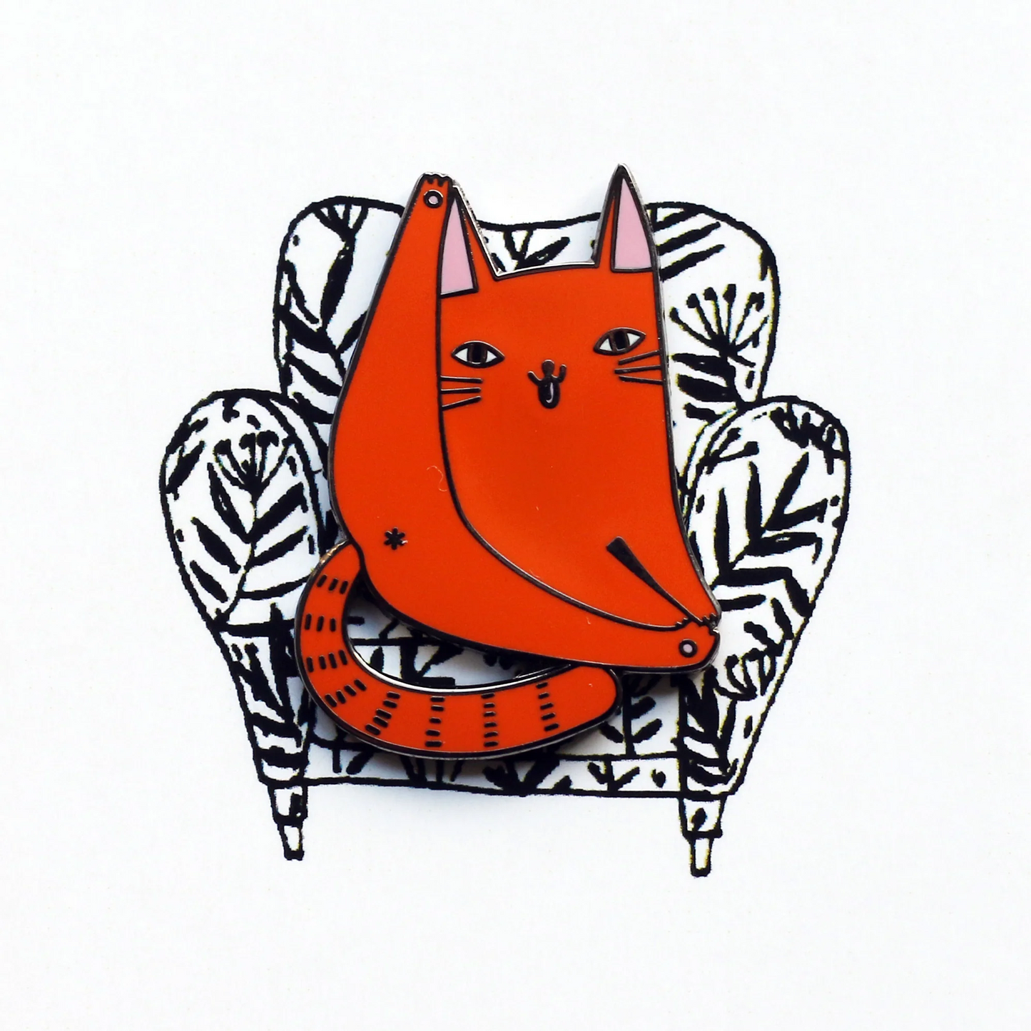 Orange cat enamel pin sitting on a zebra-patterned chair against a white cardboard header background