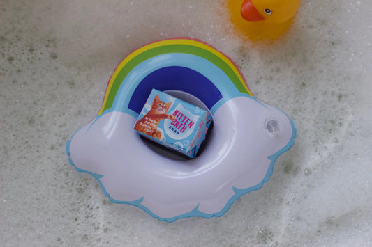 Bathtime bubbles with a rainbow floatie, a yellow duck and a bar of kitten soap.