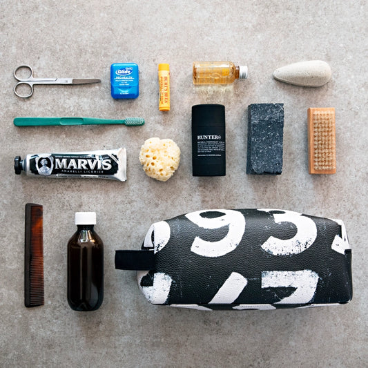 Collection of grooming products including a toothbrush, scissors, and toiletries on a textured surface.