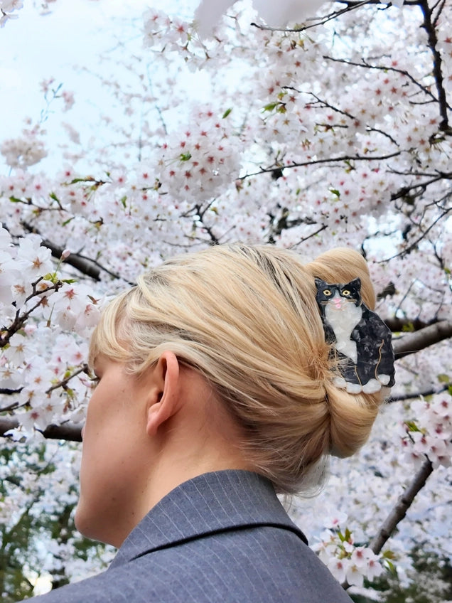 Person with a cat hair claw in their hair against a cherry blossom background