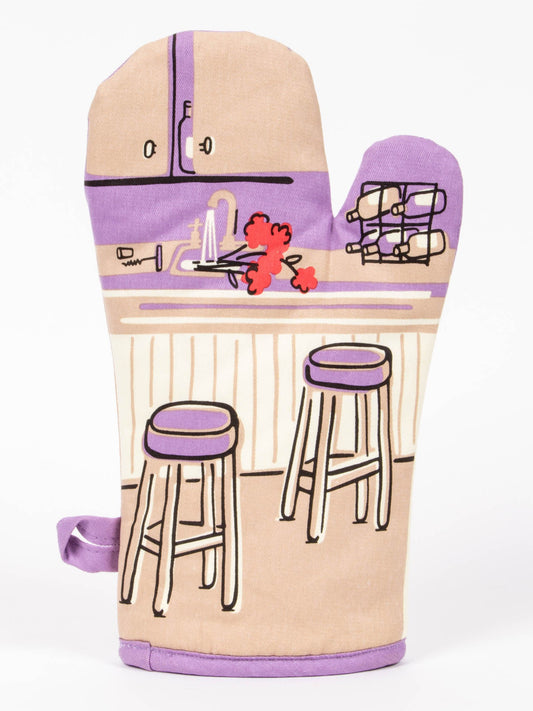 The back view BLUE Q oven mitt shows a unattended cartoon drawing. On the kitchen bench there is a sink of pouring water with a bunch of red flowers. A wine rack and a dislodged cork . Two bar stools are empty|Gizmo Gifts