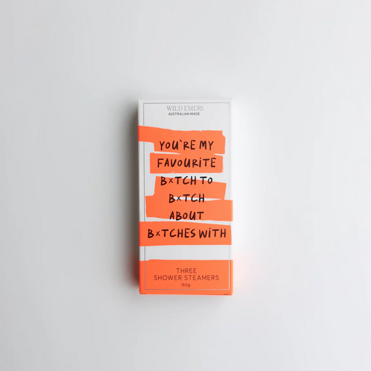 An orange package containing a trio of Wild Emery scented shower steamers. Slogan reads: You're my favourite b*tch to B*tch about b*tches with. Background is white.
