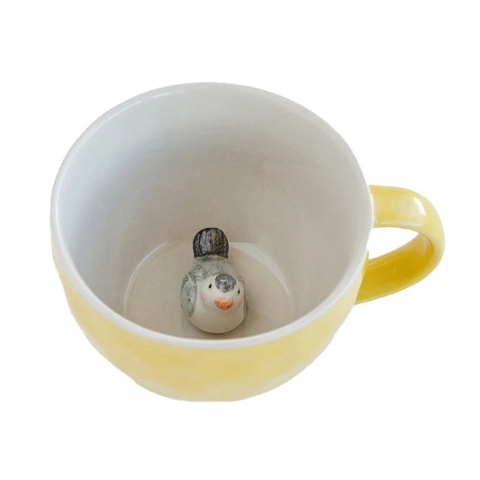 Yellow mug with a small bird figurine inside on a white background
